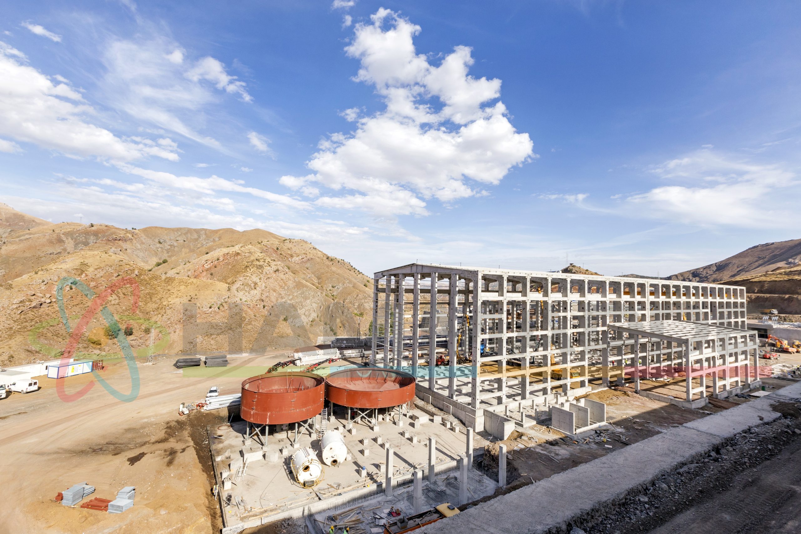 View of the ongoing industrial copper processing plant. Brown thickener tanks and concrete columns and beams that appear in the section, flotation building.